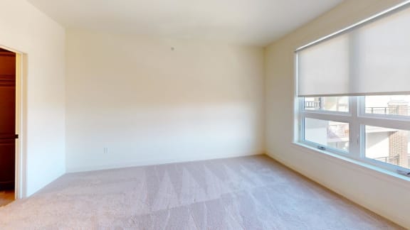 an empty living room with a large window and carpet