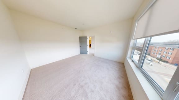 an empty living room with a large window and white walls