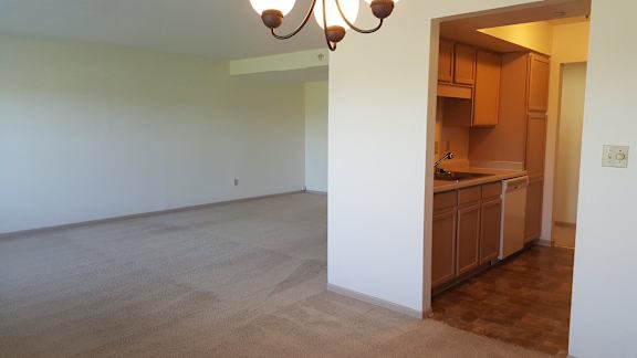 A kitchen area with wooden cabinets and a light brown floor.