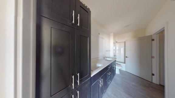 a kitchen with black cabinets and a sink and a toilet