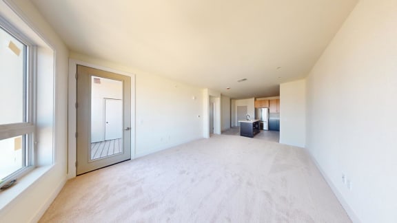 a large empty living room with white walls and a large window