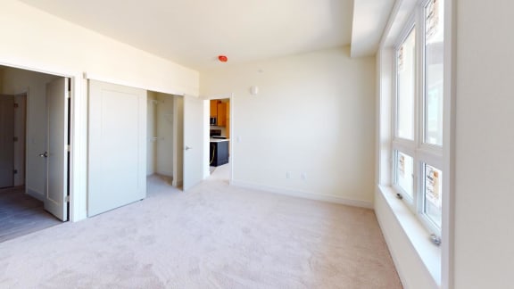 an empty living room with windows and a door to a kitchen