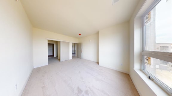 a spacious living room with white walls and a large window