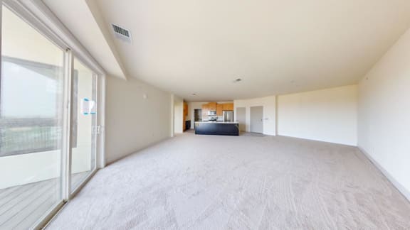 a large empty living room with a glass door to the kitchen