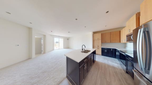 a kitchen and living room with a refrigerator and a sink