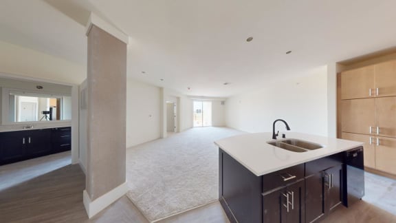 a kitchen with a sink and a large empty living room