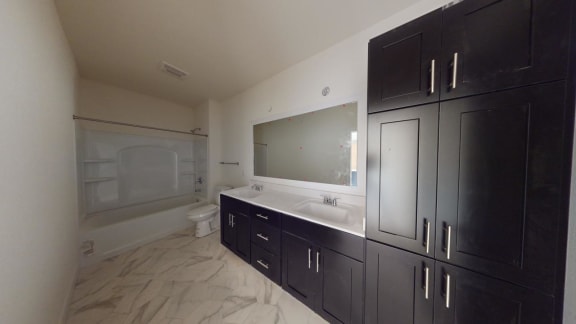 a bathroom with black cabinets and a sink and a toilet