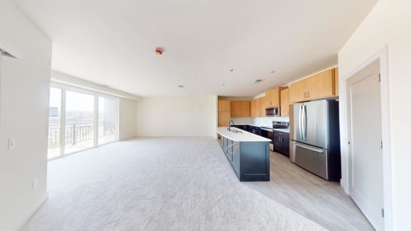 a large living room with a kitchen and a balcony