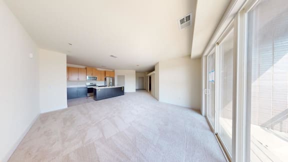 a large empty living room with a kitchen in it