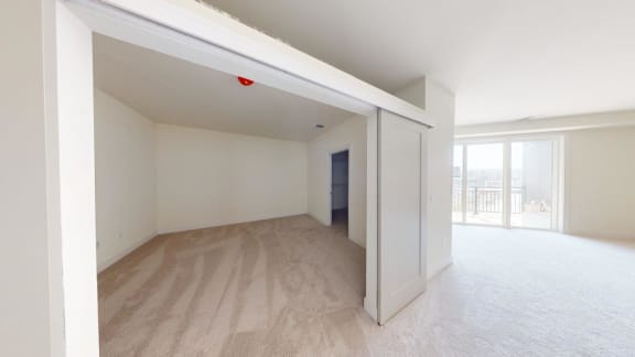 an empty living room with a door to a balcony