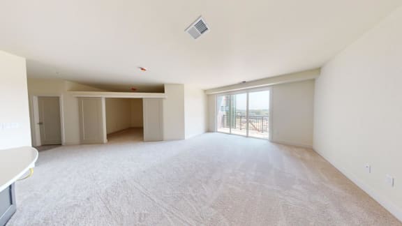 the living room and dining room of an apartment with no furniture