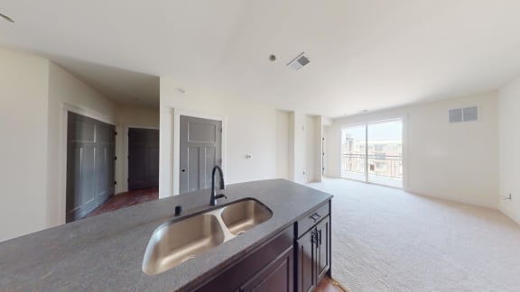 a kitchen with a sink and an empty living room