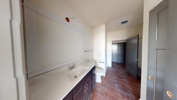 a bathroom with a sink and a toilet and a hallway