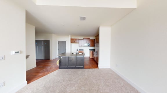 an empty living room and kitchen with hard wood flooring