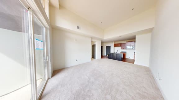 a large empty living room and kitchen with a glass door