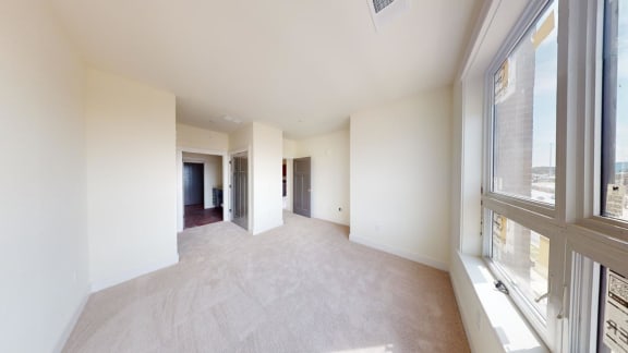 an empty living room with large windows and white walls