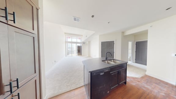 an empty living room with a kitchen with a sink