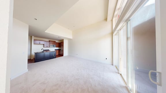 a empty living room with a kitchen in the background
