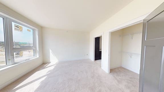 an empty living room with a large window and a closet