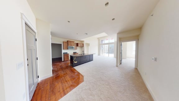 a large empty living room with a kitchen and a door