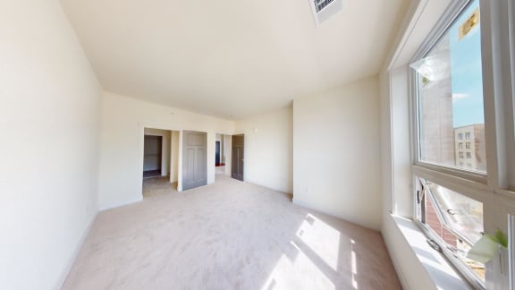 an empty living room with a large window and white walls