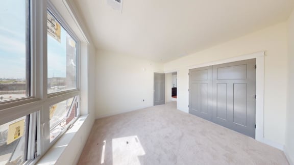 an empty living room with a gray door and a large window