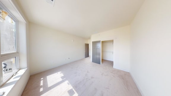 an empty living room with a large window and white walls