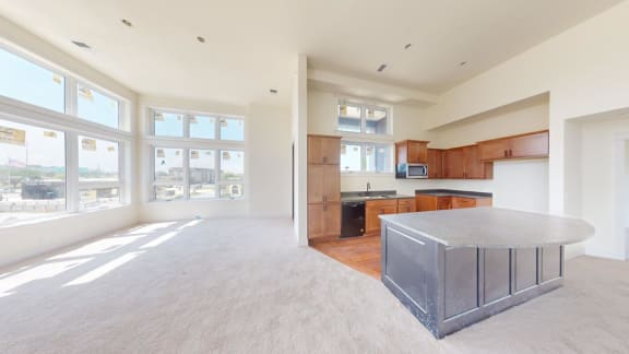 an empty living room and kitchen with a granite island