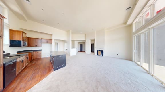 a large empty living room with a kitchen and a large window