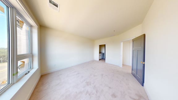 an empty living room with a large window and a door