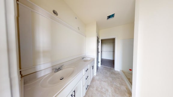 a bathroom with two sinks and a door to a hallway
