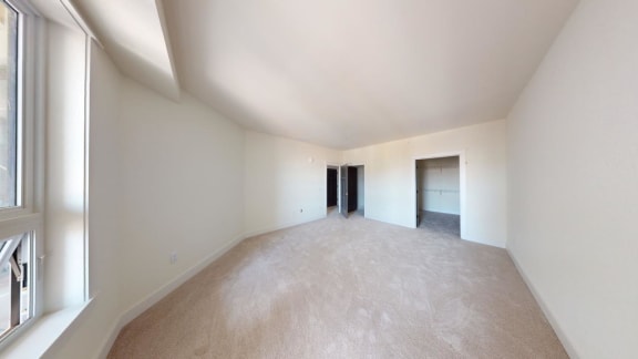 a spacious living room with white walls and a large window