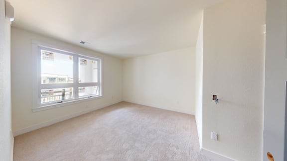 an empty room with a window and white walls