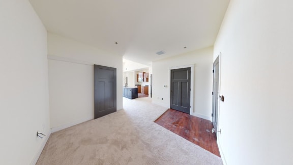 a living room with two doors and a carpeted floor