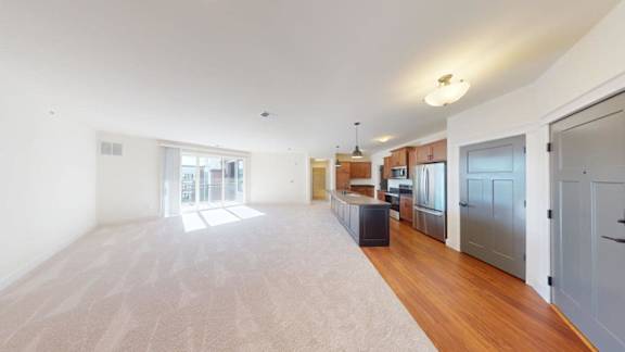 A spacious living room with a large window and a wooden floor.