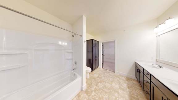 A bathroom with a white tub and a sink with a mirror.