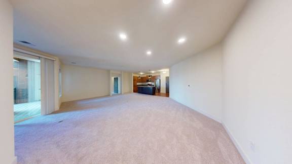 A spacious room with white walls and carpeted floor.