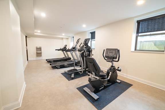 A room with a row of treadmills and elliptical machines.at The Annex Apartment, Buffalo