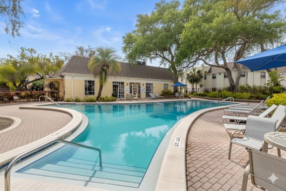 A swimming pool surrounded by lounge chairs and trees. at The Flats at Seminole Heights, Tampa, 33603