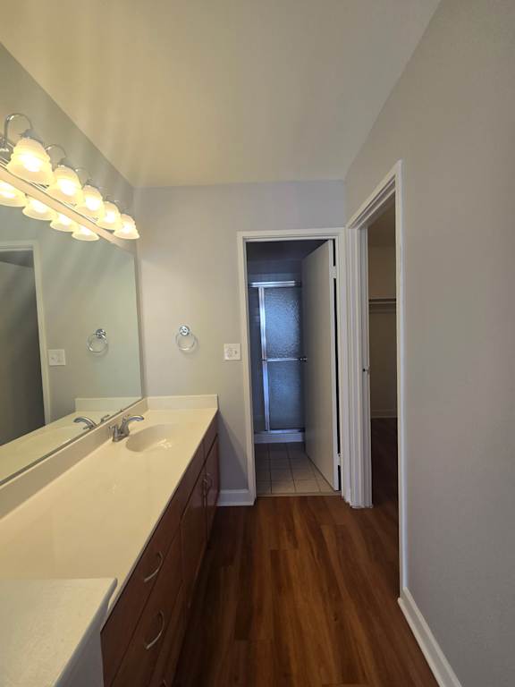 A bathroom with a mirror, light, and wooden wall.