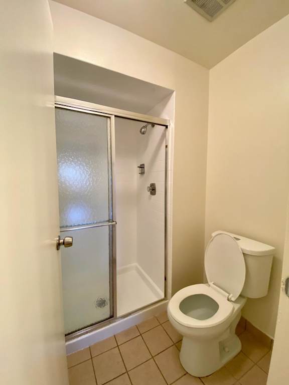 A white toilet in a small bathroom with a glass door.
