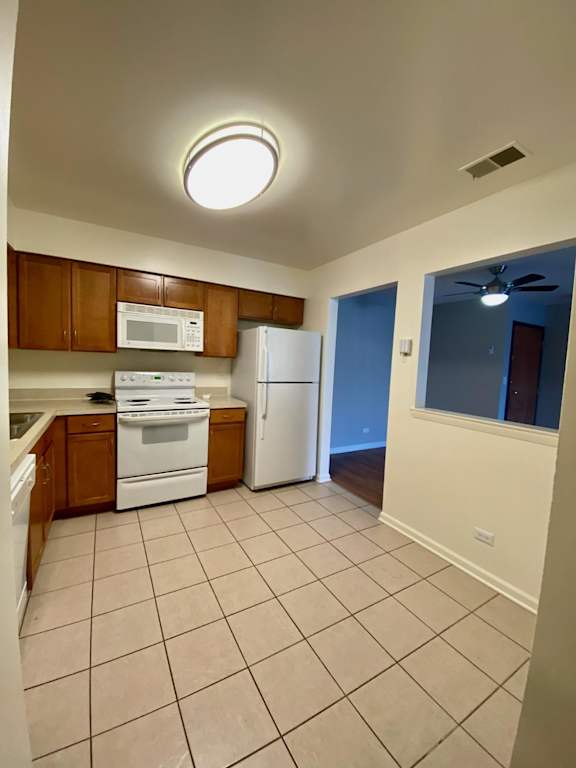 A kitchen with white appliances and brown cabinets.