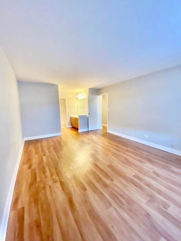 A room with wooden flooring and white walls.