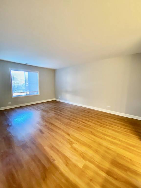 A room with wooden flooring and a window.