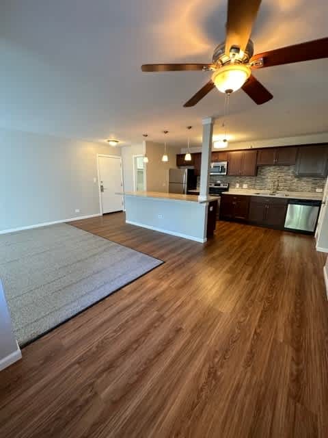 an empty living room and kitchen with a ceiling fan