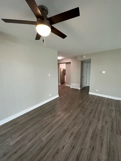 an empty living room with a ceiling fan