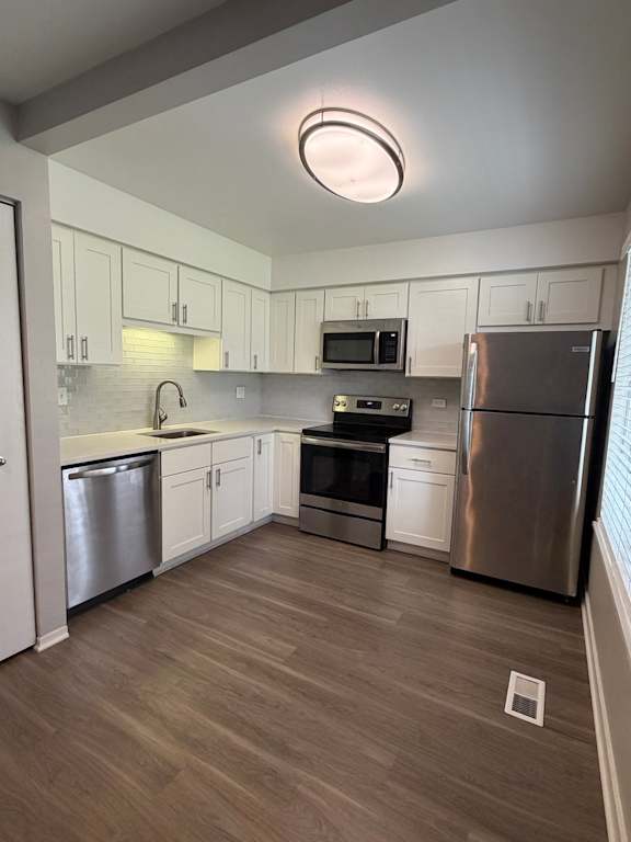 A modern kitchen with a stainless steel refrigerator and a round light on the wall.