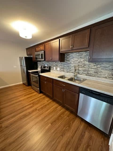 a kitchen with stainless steel appliances and wooden floors