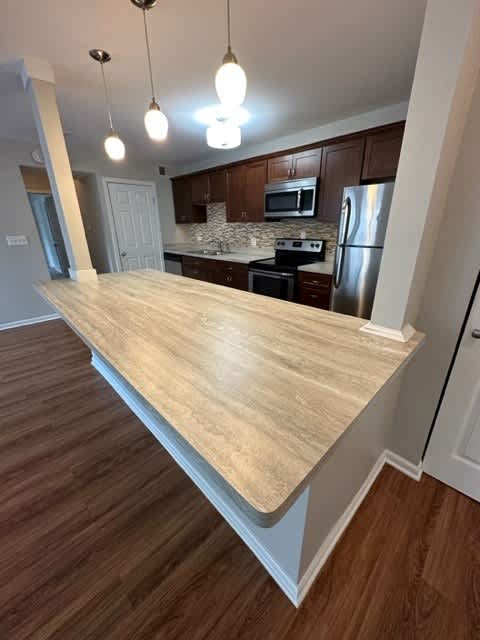 a kitchen with a large counter top and a stainless steel refrigerator