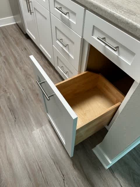 a kitchen with white cabinets and a wooden floor